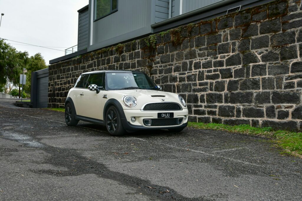 a small white car parked in front of a brick wall